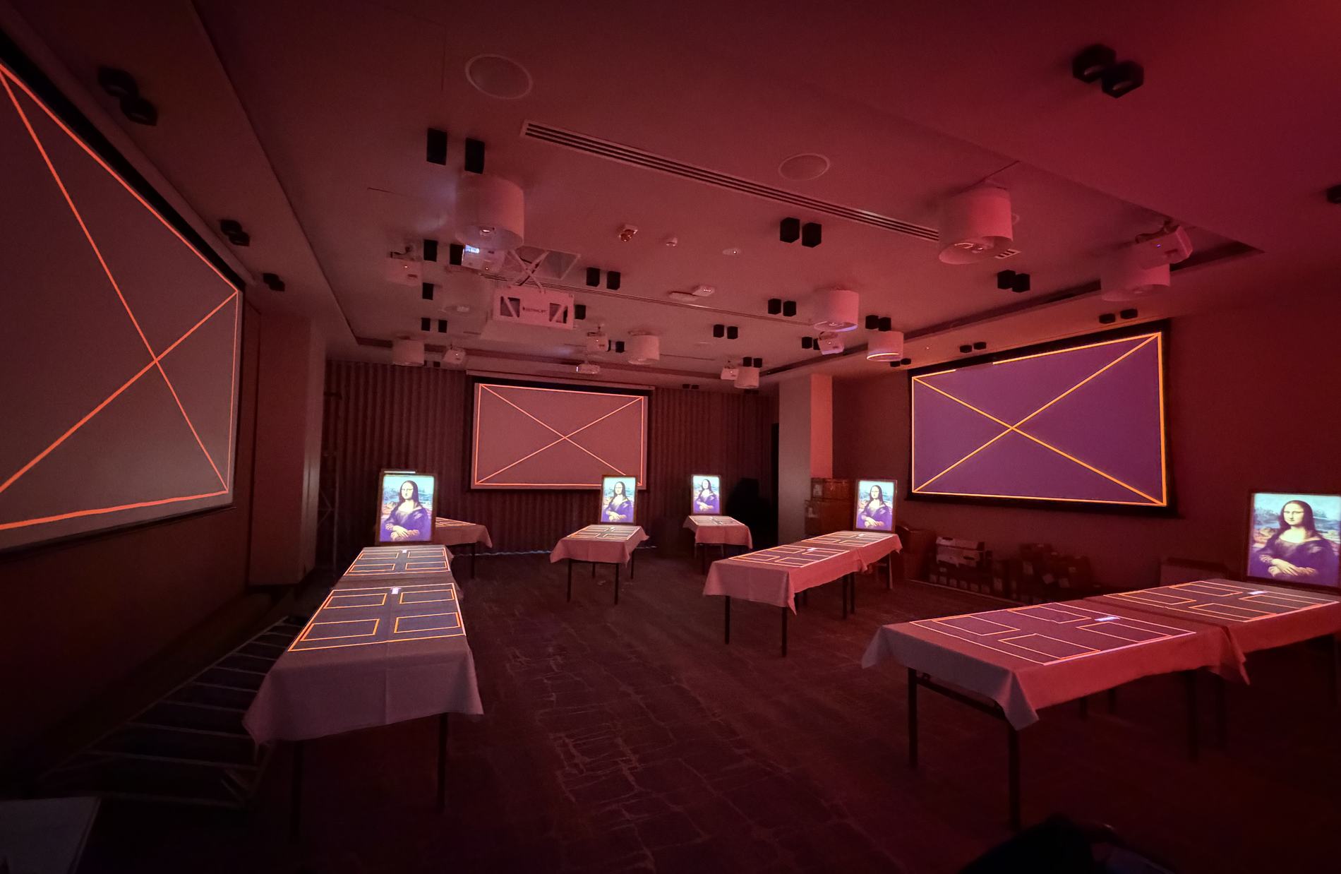 The room at night: alignment patterns glowing on four screens and every table, lit deep red