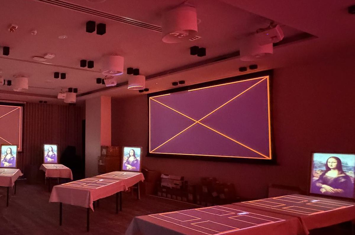 A projection screen in a dark banquet room, showing an amber alignment frame with its two diagonals